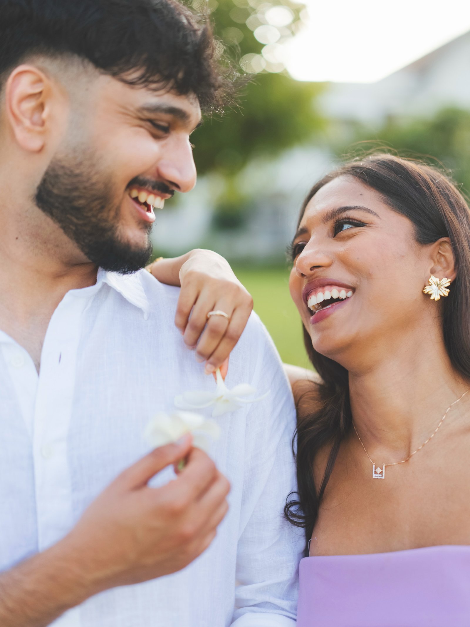 A couple sharing a joyful, candid moment with white flowers