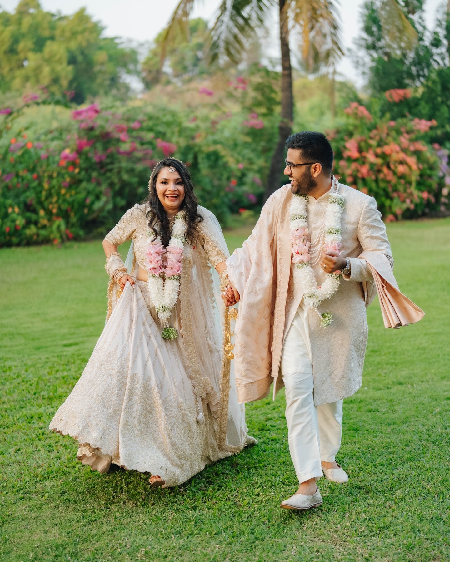 A happy couple holding hands and laughing as they stroll through the gardens